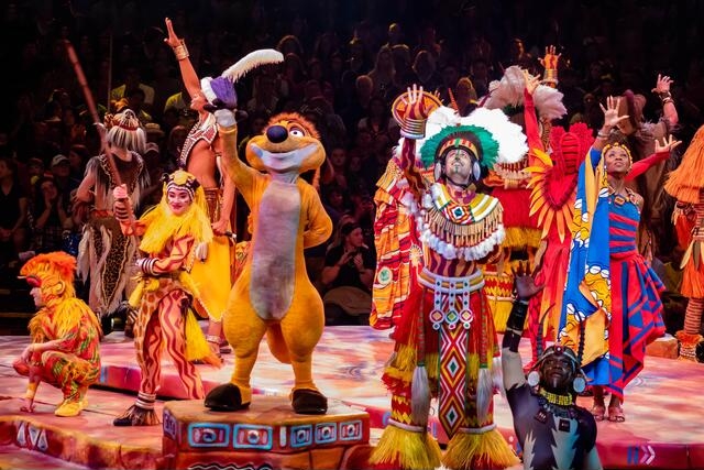 A colorful ensemble of performers dressed in vibrant costumes on a captivating stage, showcasing the mesmerizing spectacle of the Festival of the Lion King.