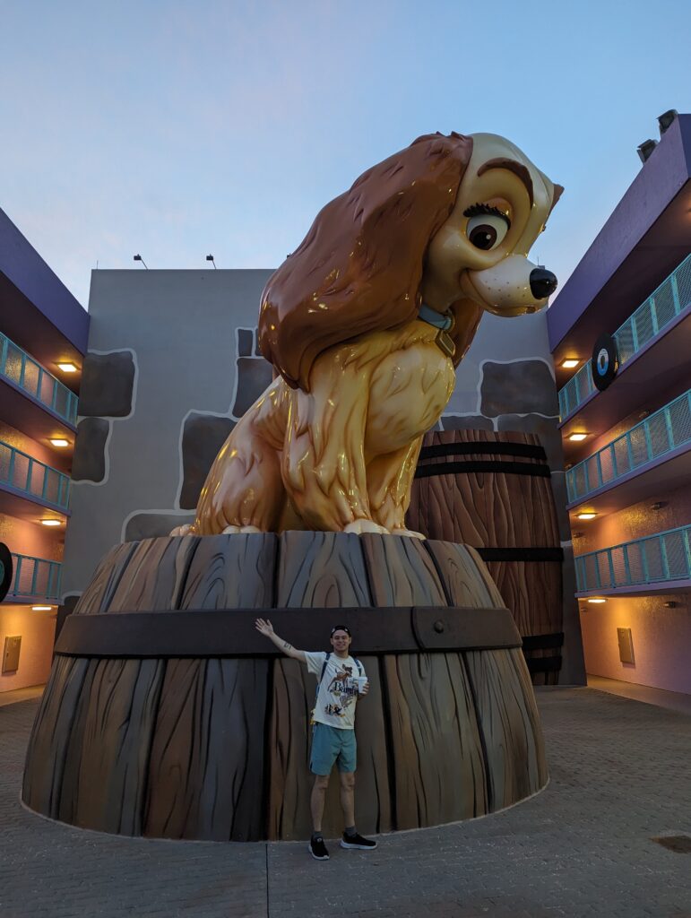 Man standing in front of Lady and the Tramp Statue at Walt Disney World at Pop Century.